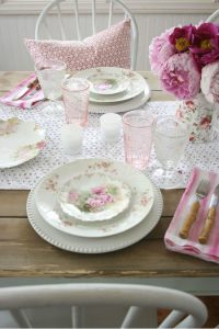 white chairs and red pillows around wooden table topped with white and pink antique china
