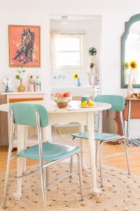 Vintage dining area with white table, blue chairs, jute rug and horse painting