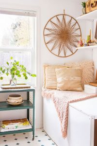 Small room with vintage green cart, rattan wall hanging, and shipping space in a vintage cottage.