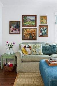 Green sofa with paintings hung above it