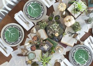An elegant halloween tablescape set with vintage plates, book pages, silver goblets and other magical elements.