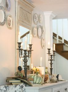 Elegant sideboard display with mirror, silver candlesticks and pumpkins