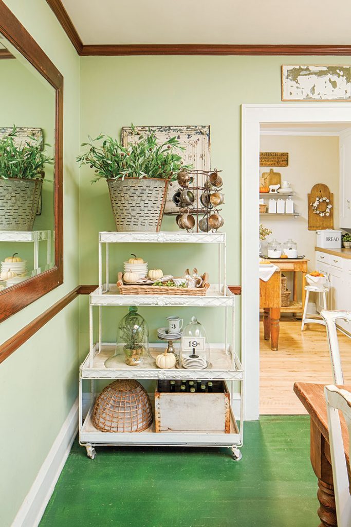 Green fall dining room with vintage collectibles on shelving