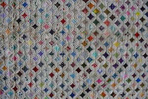 Cathedral quilts stand tall among vintage quilts with many tiny, multi-colored diamond squares.