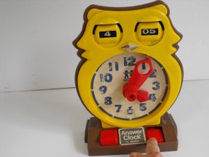 This vintage clock is made of yellow plastic in the likeness of an owl. The eyes, when open, show the hour and minutes while the body is a hand clock.