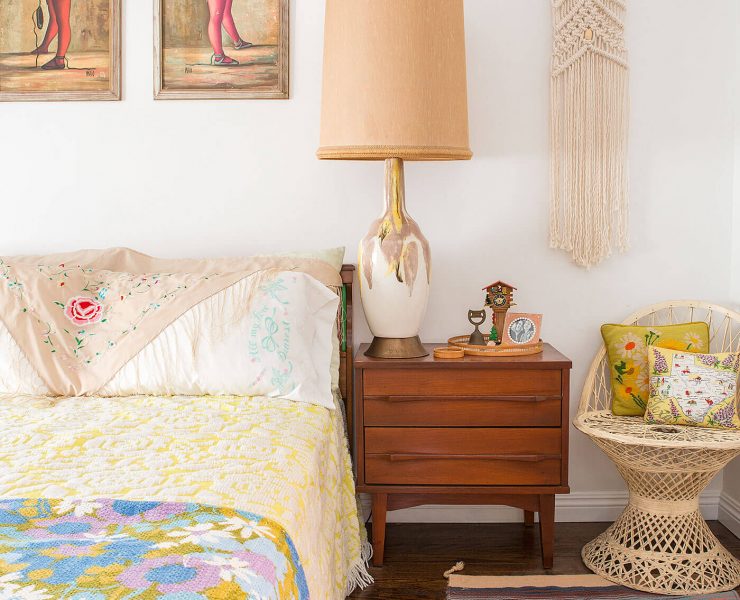 A vintage-inspired bedroom complete with a multicolor quilt, statement lamp, "Big Eye" paintings, and a slew of other antique fixtures.