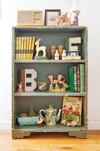 Green bookcase filled with deer figurines and books
