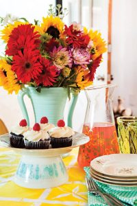 Vintage Pyrex turned upside-down to make a cake pedestal with cupcakes on top and flowers in a vintage vase.