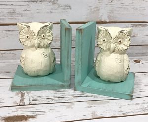 This vintage-inspired owl bookends have distressed light-blue frames with off-white owl figurines.