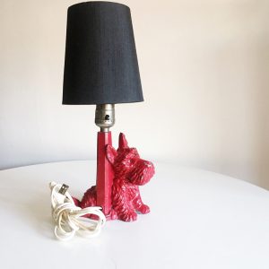 This lamp has a black fabric shade with a red stand that has a red sitting metal Scottie dog attached to the base.