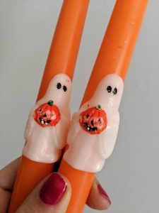 A pair of vintage Halloween orange taper candles with a little ghost holding a pumpkin at the base of each.