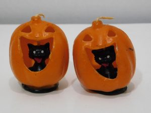 A pair of vintage Halloween pumpkin candles that look like jack-o-lanterns with black cats inside them.