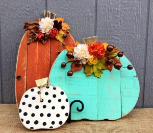 These three faux pumpkins are wood slats in the shape of pumpkins and painted orange, teal and white with black polka dots. They are embellished with artificial greenery.