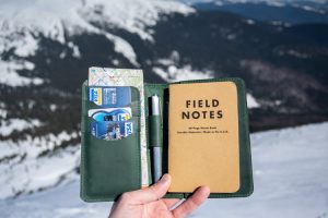 Small, green leather journal cover with credit card slots, a pen holder and a field-notes journal.