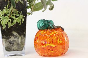 This faux pumpkin is made from hand-blown mottled orange glass with a curly green stem.