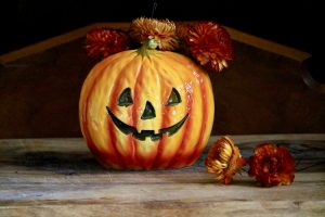 A ceramic planter painted to look like a jack-o-lantern.