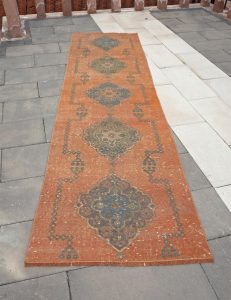 A pale, rectangular, rustic orange Bohemian carpet with a black design.