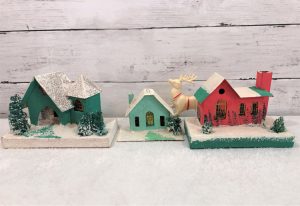 Group of three putz houses, two green and one red with snow covered rooftops.
