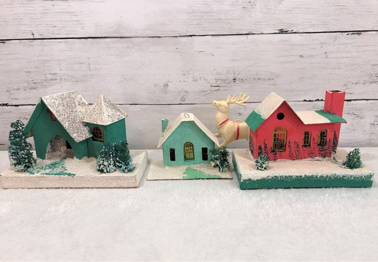 Group of three putz houses, two green and one red with snow covered rooftops.