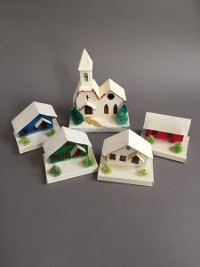 Group of five putz houses with snow covered rooftops and different colors.