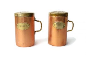 Vintage copper salt and pepper shakers with brass lids, handles and labels.