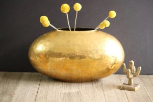 Hammered brass vase in the shape of a wide bowl.