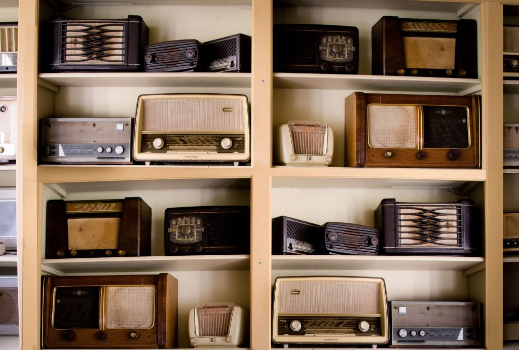 A collection of antique radios placed in an open-shelving scheme.