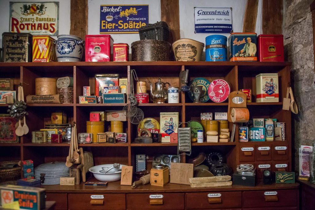 A collection of multicolored antiques in a vintage wood open-shelving compartment at an estate sale.