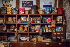 A collection of multicolored antiques in a vintage wood open-shelving compartment at an estate sale.