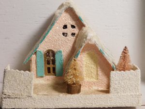 Glittery, pale pink putz house with pale blue roof and shutters with faux snow.