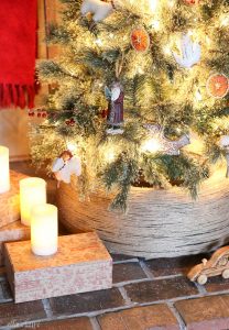 A Christmas tree stand made out of a used tire that is wrapped in twine.