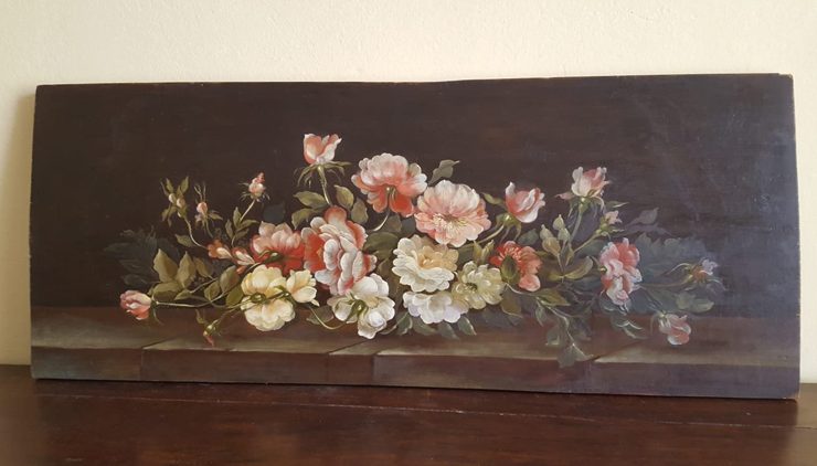 Pink and white, leafy flowers on a darkly painted wood board.