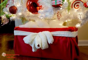 A Christmas tree stand with a cloth white belt and red fabric surrounding its exterior.
