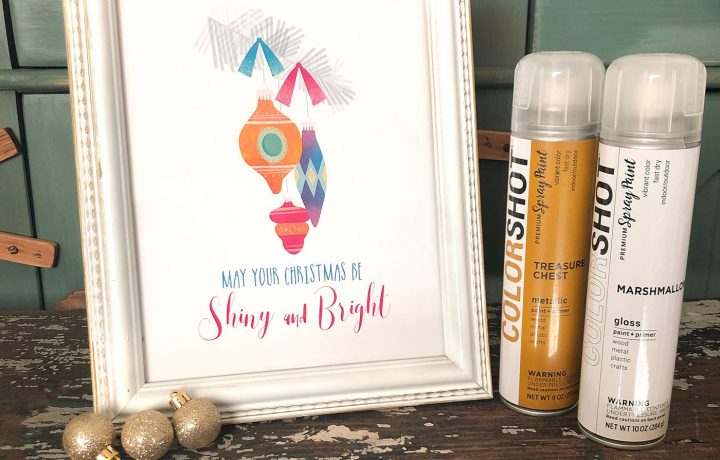 A white and gold frame showcases a holiday art printable with Shiny Brite ornaments. COLORSHOT spray paint is the product.