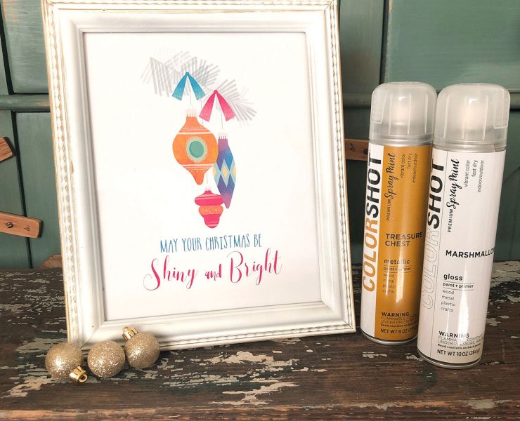 A white and gold frame showcases a holiday art printable with Shiny Brite ornaments. COLORSHOT spray paint is the product.