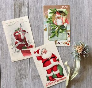 Three antique holiday postcards with Santa on them.