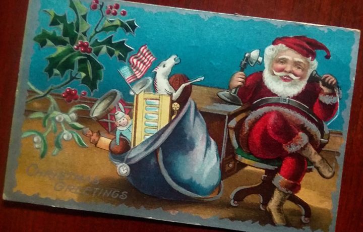 Santa chatting on an old-fashioned telephone with his sack of toys beside him.