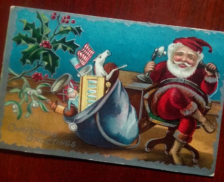 Santa chatting on an old-fashioned telephone with his sack of toys beside him.