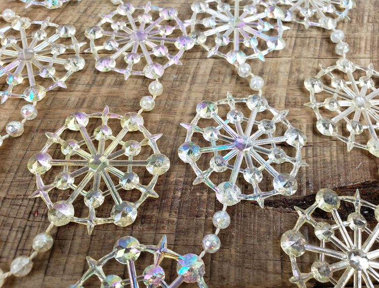 Clear plastic snowflake garland with a rainbow sheen.