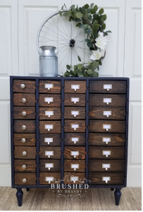Old-style apothecary cabinet with dark wood drawers and black edges.