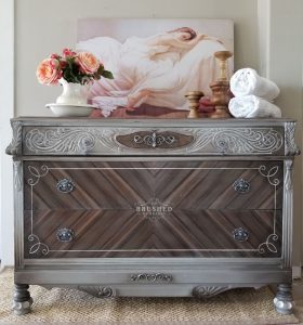 Small dresser painted gray with a wood chevron pattern.