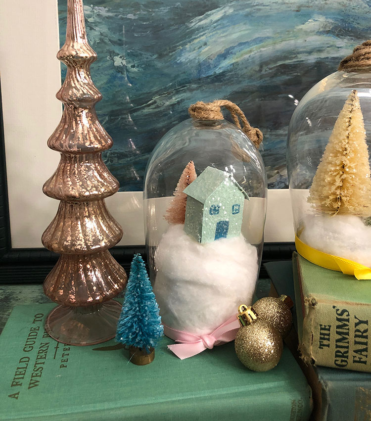 Wine glass cloche vignette with pink glass tree, gold ornaments and a house on a snowy hill