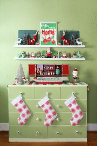 A midcentury-themed vignette boasts green and red holiday decor with an ornament print at the center.