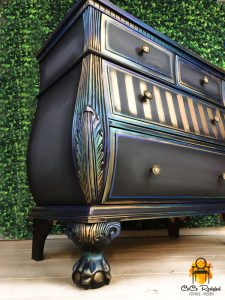 Dark blue dresser with rainbow-metallic accents and stripes on one drawer.