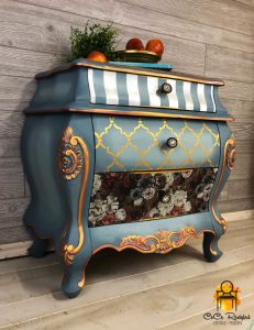 Dusty blue painted side table with drawers, each with a different pattern.