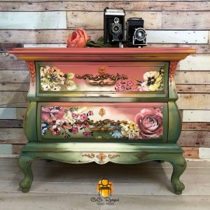 Green and rosy-pink painted dresser with floral designs on the drawers.