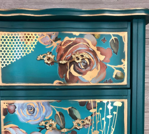 A close-up shot of the blue and gold floral painted corner of a CeCe Hunted painted dresser.