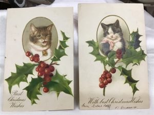 Two antique holiday postcards with cat portraits on them.