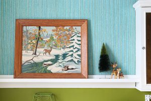 A snowy scene painting pops against a blue and green wall.