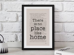 A framed book page with the quote "There is no place like home" written over it in typewriter font, a perfect gift for book lovers.